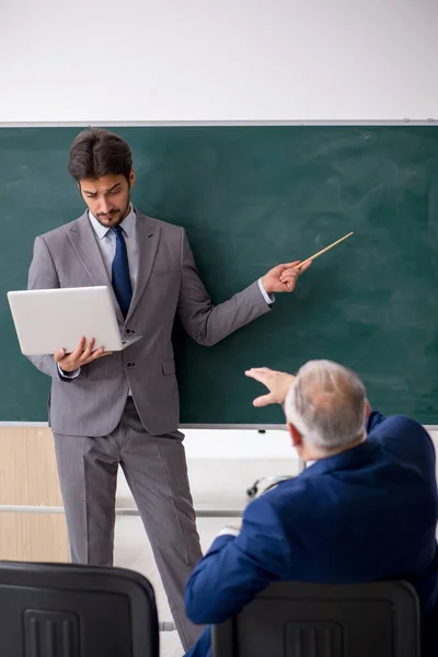 Młody mężczyzna pracownik i stary szef przed tablicą — Zdjęcie stockowe