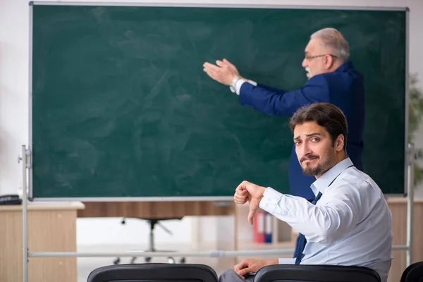 Oude mannelijke leraar en jonge mannelijke student voor het groene bord — Stockfoto