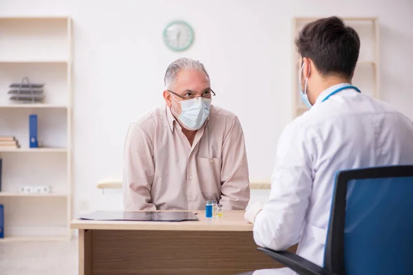 Gammal manlig patient besöker ung manlig läkare i vaccinationsgrupp — Stockfoto