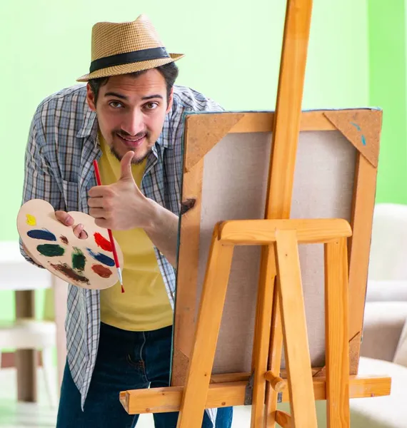 Молодой художник работает над новой картиной в своей студии — стоковое фото