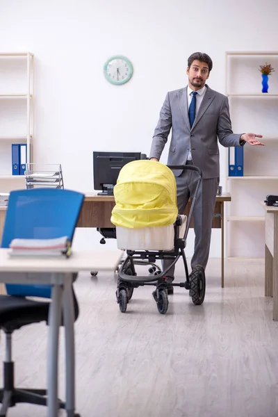 Joven empleado masculino que cuida a recién nacido en el lugar de trabajo —  Fotos de Stock