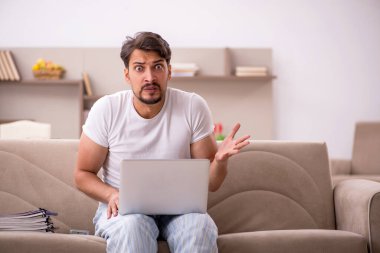 Genç erkek çalışan salgın sırasında evden çalışıyor.