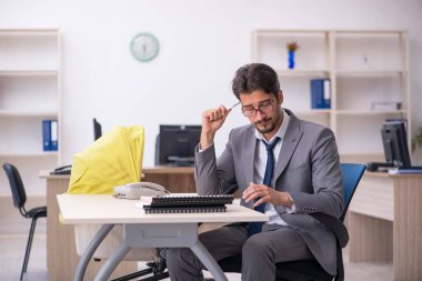 Genç erkek çalışan işyerinde yeni doğan çocuğa bakıyor.