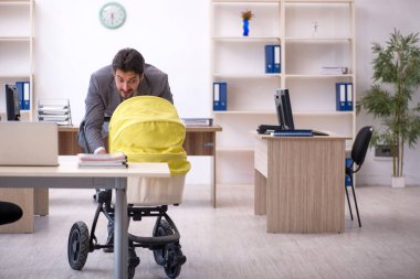 Genç erkek çalışan işyerinde yeni doğan çocuğa bakıyor.