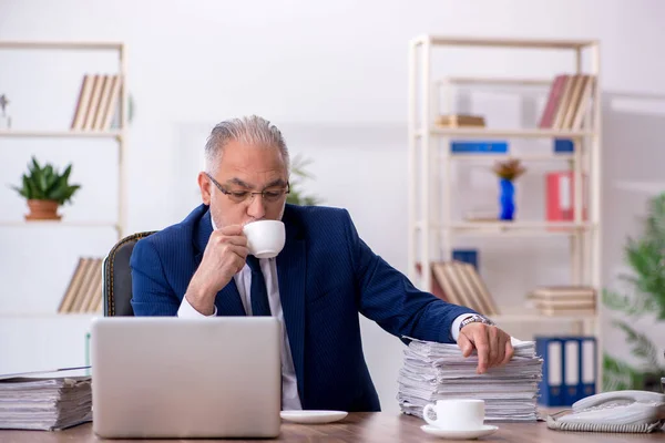 Gammal manlig anställd dricker kaffe under rasten — Stockfoto