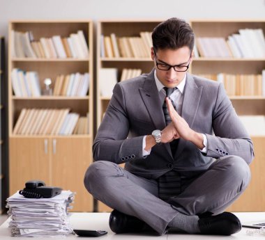 Genç işadamı ofiste meditasyon yapıyor.