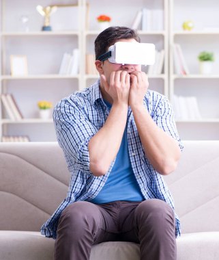 Evde sanal gerçeklik gözlüklü bir adam oynuyor.