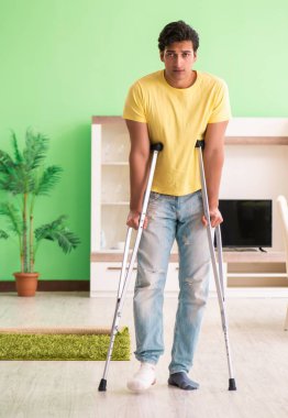 Genç adam koltuk değnekleriyle evde geçirdiği kazadan sonra iyileşiyor.