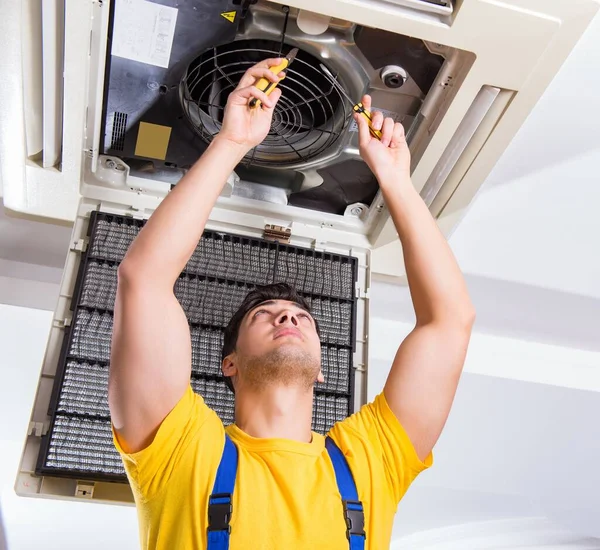 Reparador reparando la unidad de aire acondicionado del techo — Foto de Stock