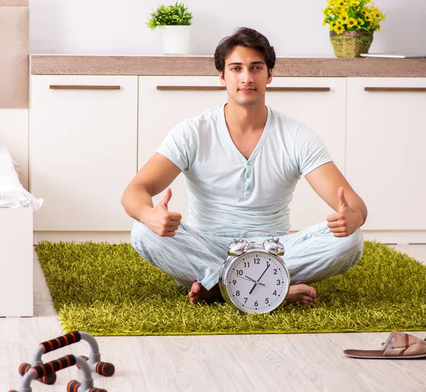 Jongeman doet yoga in slaapkamer in time management concept — Stockfoto