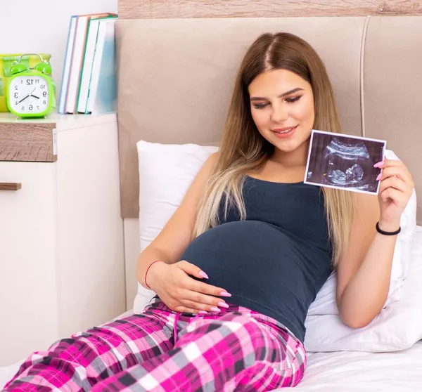 Šťastná mladá těhotná žena v posteli — Stock fotografie