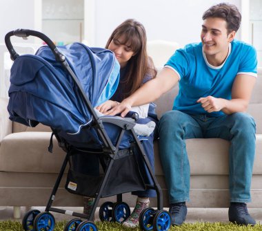 Bebekleri bebek arabasında oturan genç ebeveynler.