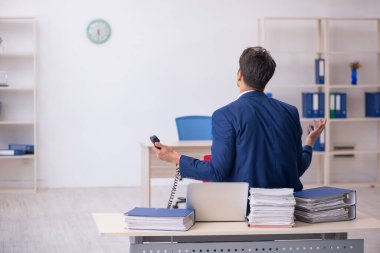 Genç bir erkek çalışan ve ofiste çok fazla iş var.