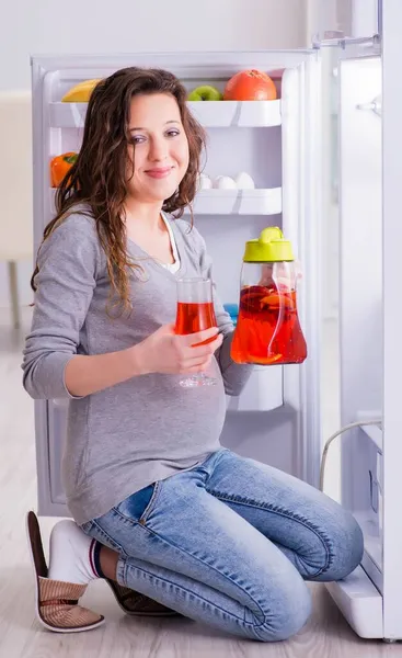 Gravid kvinna nära kylskåp letar efter mat och snacks — Stockfoto