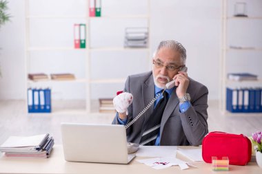 Ofiste elini kesen yaşlı bir erkek.