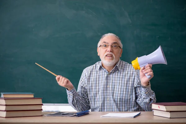 Alter männlicher Lehrer mit Megafon im Klassenzimmer — Stockfoto