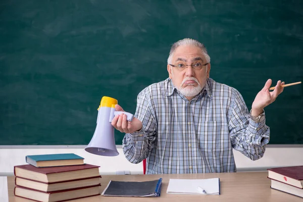 Oude mannelijke leraar met megafoon in de klas — Stockfoto