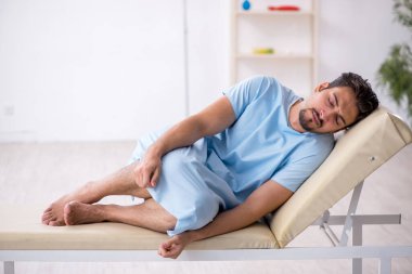 Genç erkek hasta hastanede doktor bekliyor.