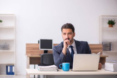 Genç erkek çalışan işyerinde oturuyor.