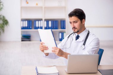 Klinikte çalışan genç erkek doktor.