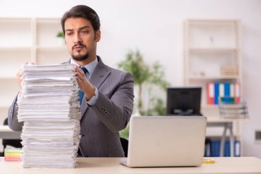 Ofisteki aşırı işten memnun olmayan genç bir erkek işçi.