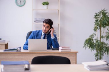 Genç erkek çalışan ofiste oturuyor.