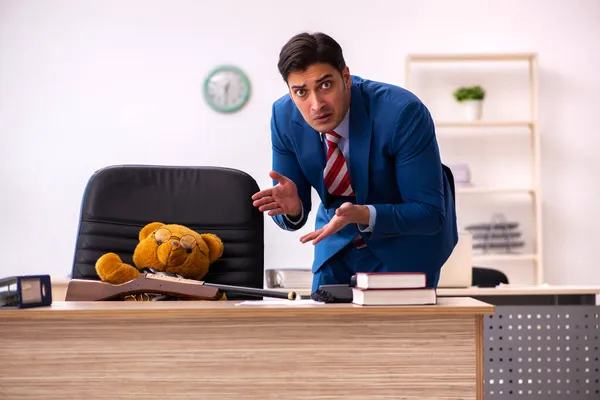 Jovem funcionário masculino e seu chefe urso de brinquedo em conceito engraçado — Fotografia de Stock