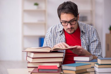 Genç bir erkek öğrenci ve sınıfta çok fazla kitap var.