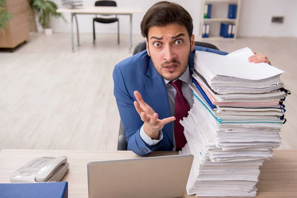 Young male employee and too much work in the office — Stock Photo, Image