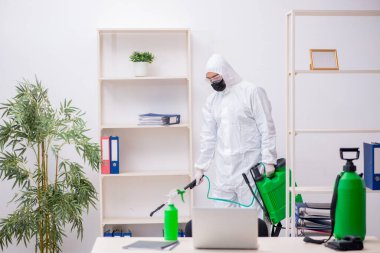 Young male contractor disinfecting office during pandemic