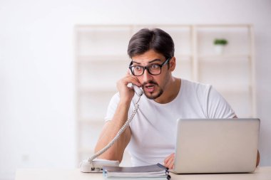 Genç erkek çalışan serbest çalışan ofiste oturuyor.