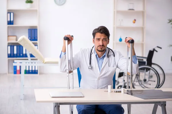 Junger Arzt mit Krücken in der Klinik — Stockfoto