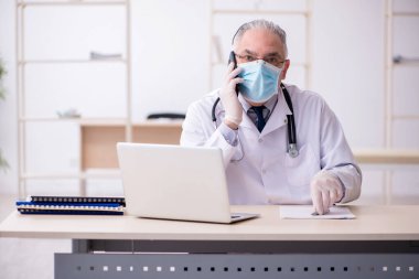Klinikte çalışan yaşlı erkek doktor.