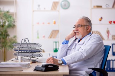Klinikte çalışan yaşlı erkek doktor.