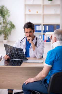 Yaşlı erkek hasta genç erkek doktor radyolojisti ziyaret ediyor.
