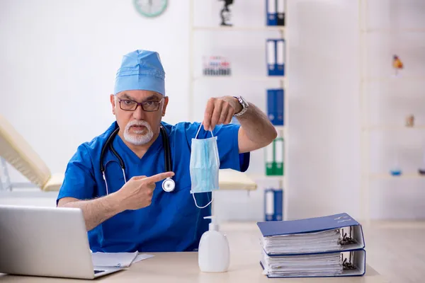 Viejo médico que trabaja en la clínica durante una pandemia — Foto de Stock