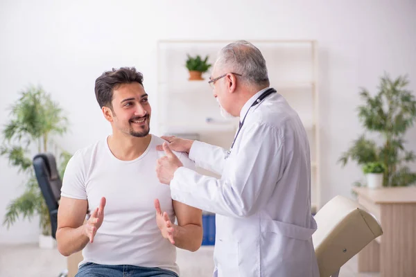 Jeune patient de sexe masculin visitant un vieux médecin — Photo