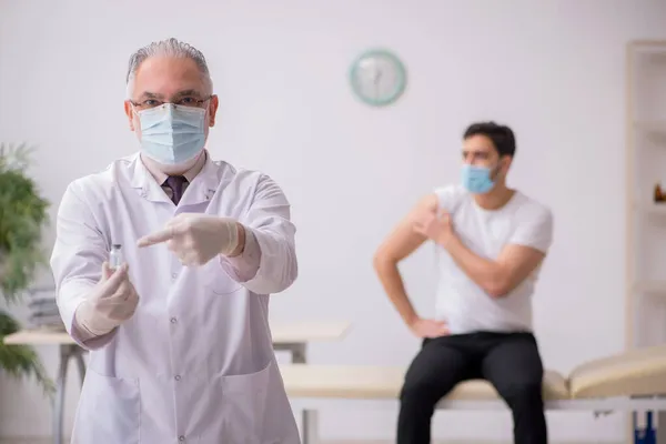 Junge männliche Patientin besucht alten Arzt im Impfpass — Stockfoto