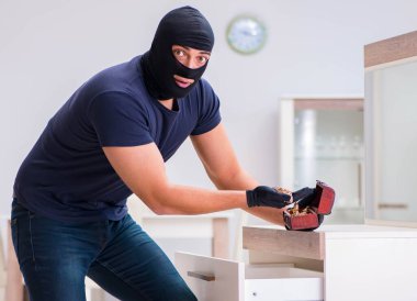 Robber wearing balaclava stealing valuable things clipart