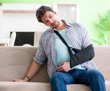 Eli yaralı genç bir öğrenci kanepede oturuyor.