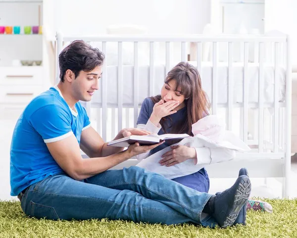 Jonge ouders met hun pasgeboren baby zittend op het tapijt — Stockfoto