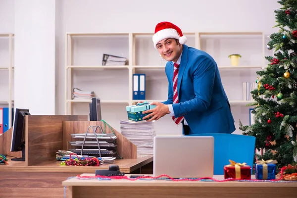 Ung mandlig medarbejder fejrer jul på arbejdspladsen - Stock-foto