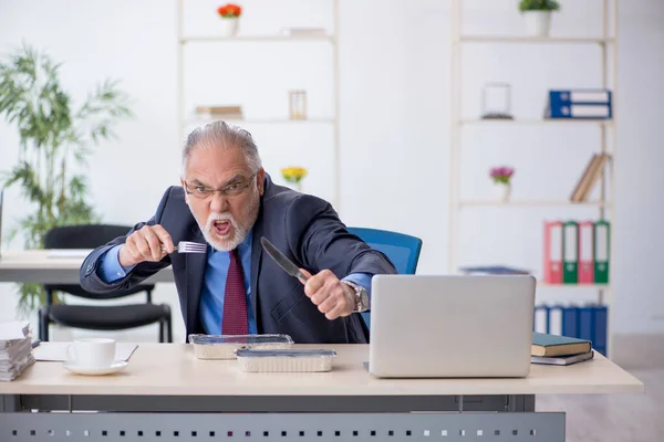 Old male employee having breakfast in the office — Stock Photo, Image