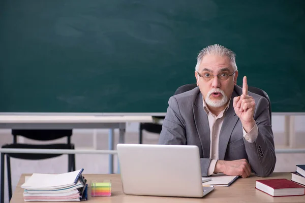 Old male teacher in front of blackboard — Stock Photo, Image