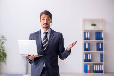 Genç erkek çalışan işyerinde oturuyor.