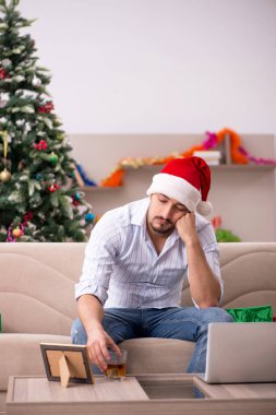 Genç adam Noel 'i evde yalnız kutluyor.