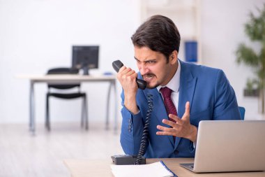 Ofisteki aşırı işten memnun olmayan genç bir erkek işçi.