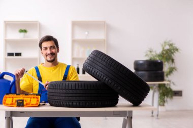 Atölyede lastiği olan genç bir erkek tamirci.