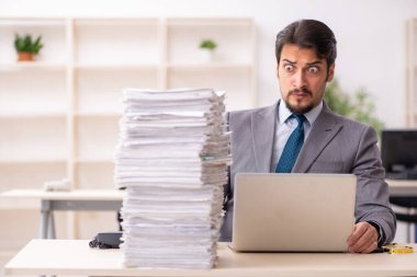 Ofisteki aşırı işten memnun olmayan genç bir erkek işçi.