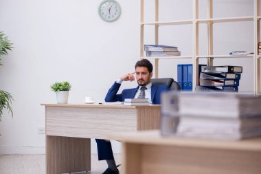 Genç bir erkek çalışan ve ofiste çok fazla iş var.